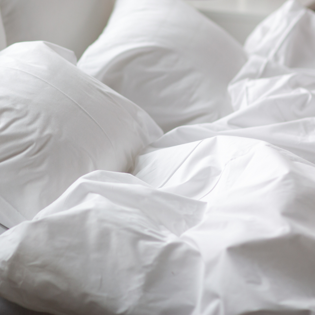 Elegant minimalist bedroom featuring breathable white cotton bed sheets, ideal for a fresh and airy look.