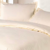 Neatly folded cream striped 4-piece bed sheet set including a fitted sheet, flat sheet, and two pillowcases, styled with a clean minimal aesthetic.