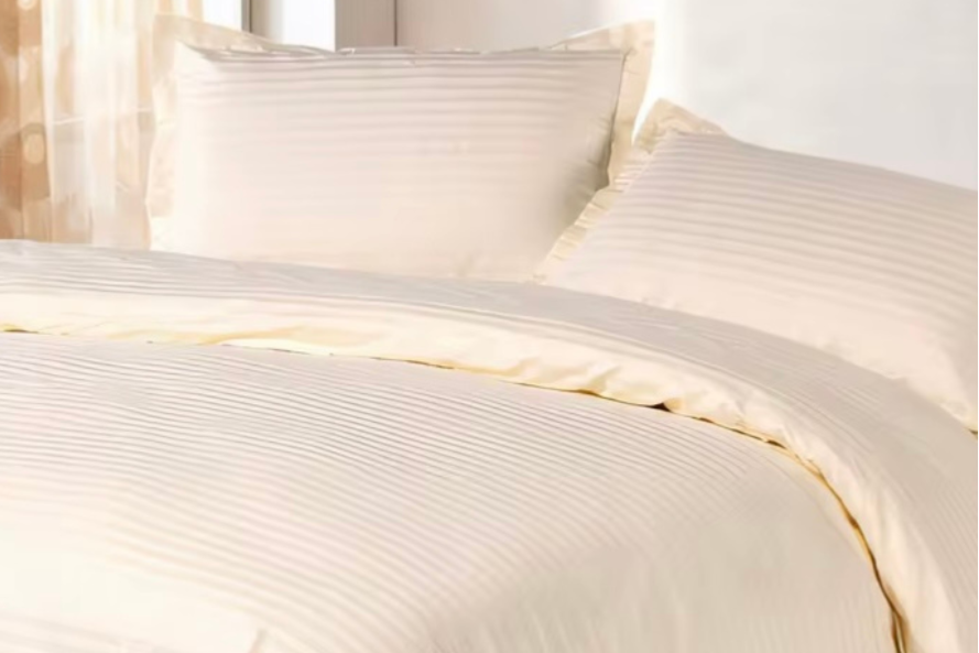 Neatly folded cream striped 4-piece bed sheet set including a fitted sheet, flat sheet, and two pillowcases, styled with a clean minimal aesthetic.